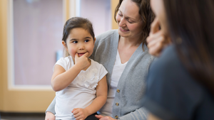 A speech therapist works with a young girl on pronunciation.