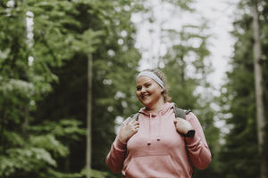 Young woman smiling while hiking in forest