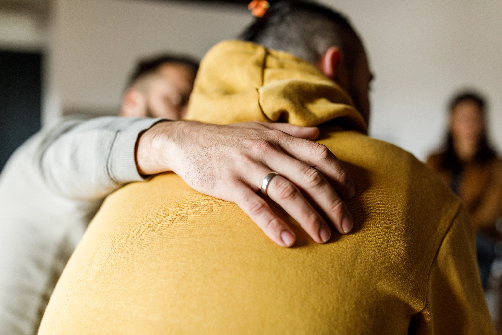 Man embracing his friend who is sharing his story at the group therapy session