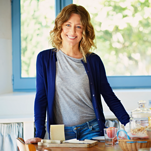 Portrait of happy woman standing at breakfast table in kitchen