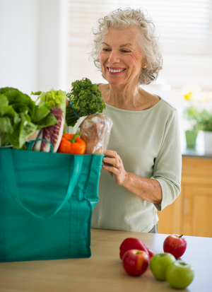 Senior woman with grocery bag in kitchen