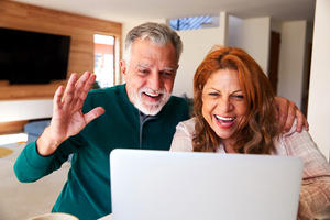 Senior couple at home with laptop having video chat with family